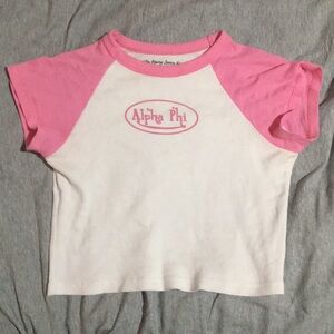 Cute baby tee with pink sleeves, has the logo “alpha phi” on the front
